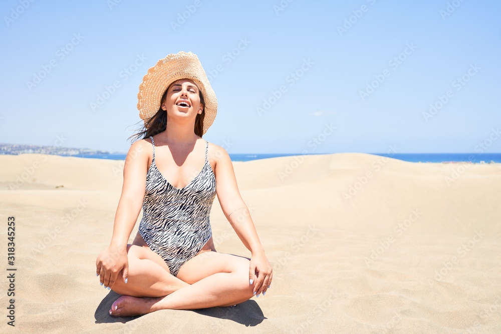 Young beautiful woman sunbathing and relaxing sitting on the sand doing yoga poses at maspalomas dunes bech Young beautiful woman sunbathing and relaxing sitting on the sand doing yoga poses at maspalomas dunes bech