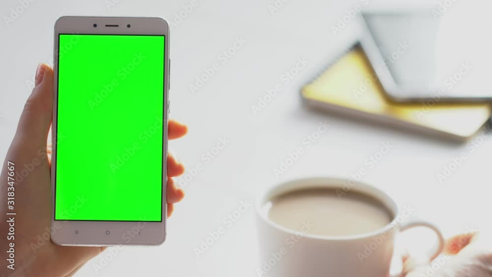 business woman using smartphone viewing green screen on mobile phone browsing chroma key online watching enjoying drinking coffee reading social media close up hands business woman using smartphone viewing green screen on mobile phone browsing chroma key online watching enjoying drinking coffee reading social media close up hands