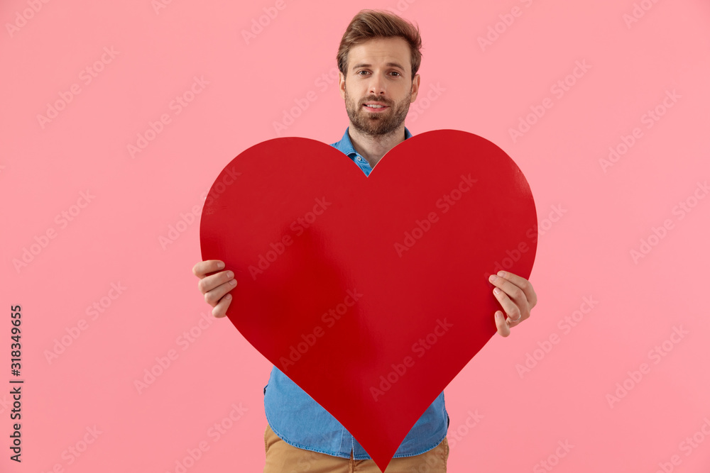 happy casual guy smiling and holding big red heart happy casual guy smiling and holding big red heart