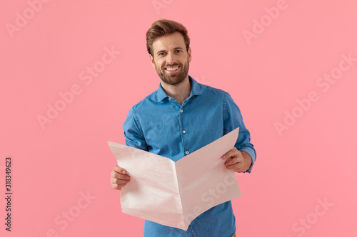 happy casual man in denim shirt holding newspaper and smiling