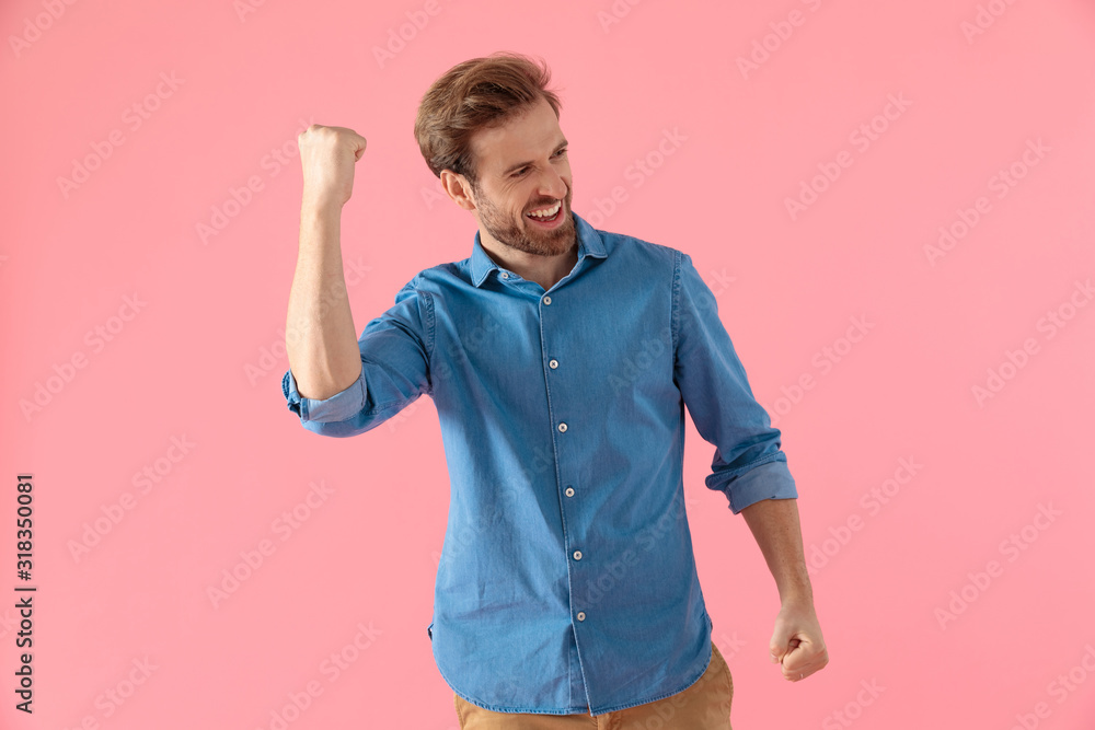 enthusiastic casual man holding fist up and celebrating victory enthusiastic casual man holding fist up and celebrating victory