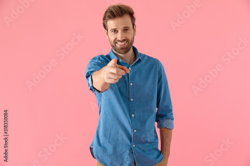 happy casual man in denim shirt smiling and pointing finger