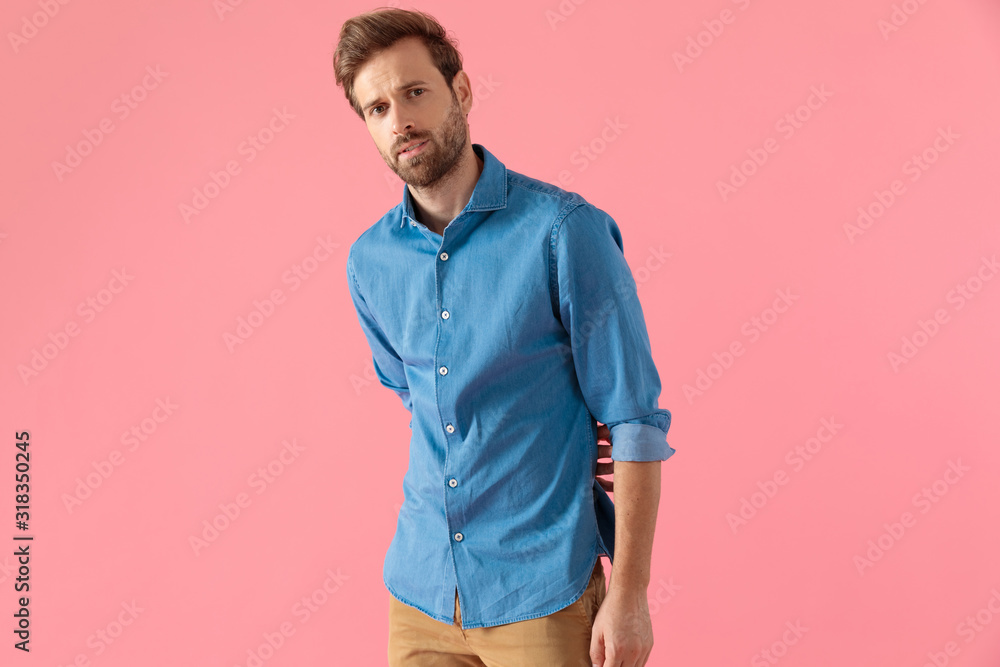 young casual man in denim shirt holding hand to back young casual man in denim shirt holding hand to back