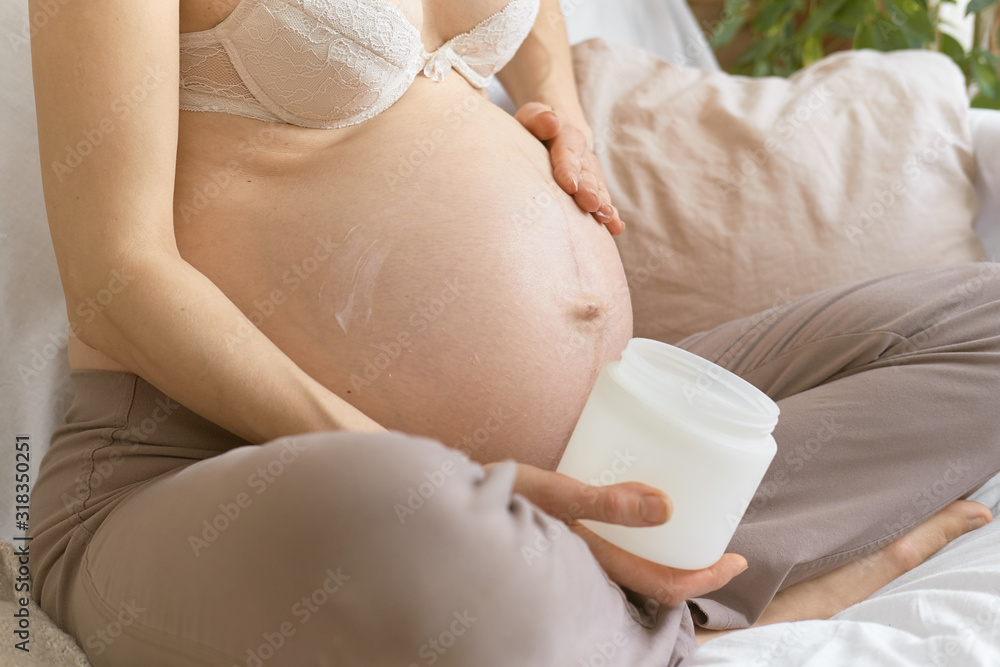 Pregnancy. Stretch marks on the stomach. A pregnant woman smears a cream on her stomach. Without a face. Pregnancy. Stretch marks on the stomach. A pregnant woman smears a cream on her stomach. Without a face.