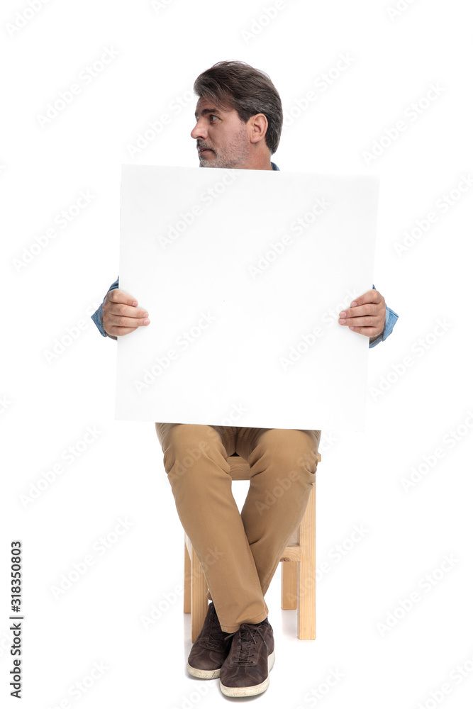 Pensive casual man an empty holding billboard and looking away Pensive casual man an empty holding billboard and looking away