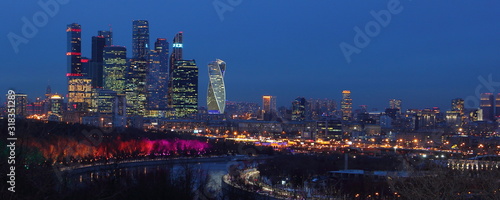 Russia, Moscow city Business center skyscrapers with urban buildings, Moscow river turn with painted illuminated trees background, panoramic winter night view from Vorobyovy Gory observation deck