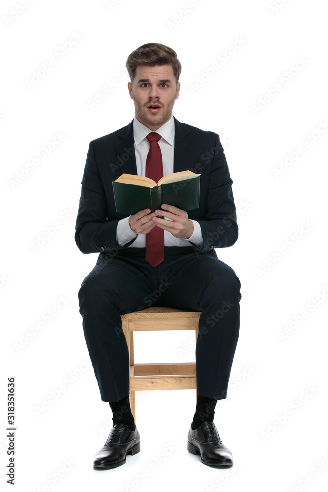 shocked young businessman in suit reading a book shocked young businessman in suit reading a book