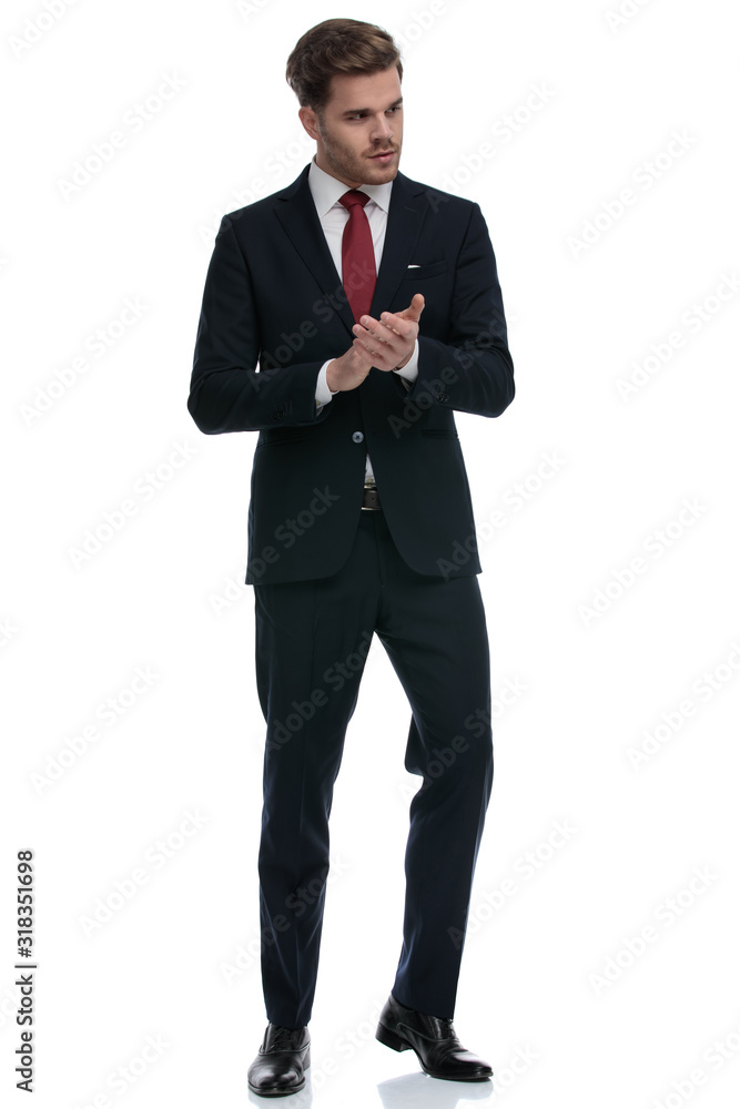 elegant businessman in suit rubbing palms and looking to side elegant businessman in suit rubbing palms and looking to side