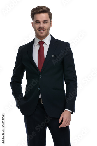 young businessman holding hands in pockets and smiling