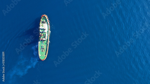 Aerial drone top down photo of tug boat cruising in industrial carrier logistics terminal