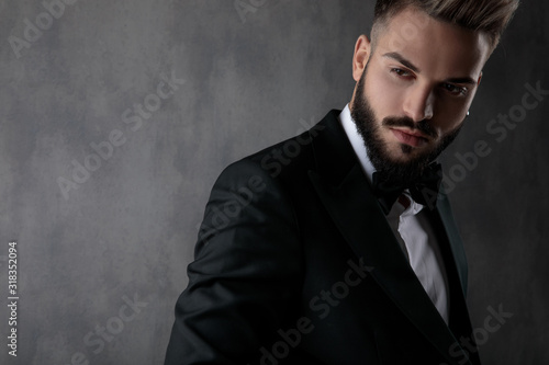 businessman wearing black tuxedo posing cool looking away