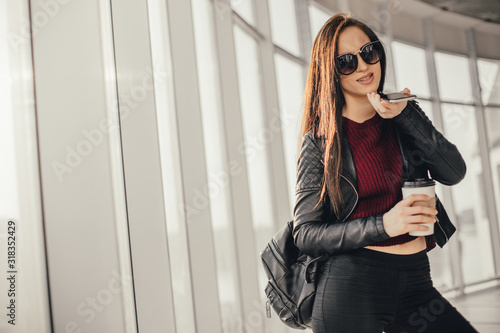 Young pretty woman waitin for friend with cup of coffee and talking by phone photo