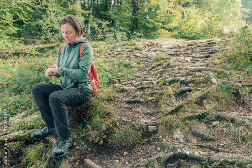 Female hiker checking on smart fitness tracker