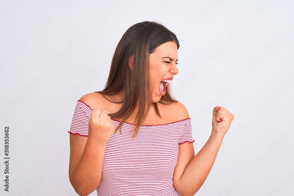 Portrait of beautiful young woman standing over isolated white background very happy and excited doing winner gesture with arms raised, smiling and screaming for success. Celebration concept. Portrait of beautiful young woman standing over isolated white background very happy and excited doing winner gesture with arms raised, smiling and screaming for success. Celebration concept.