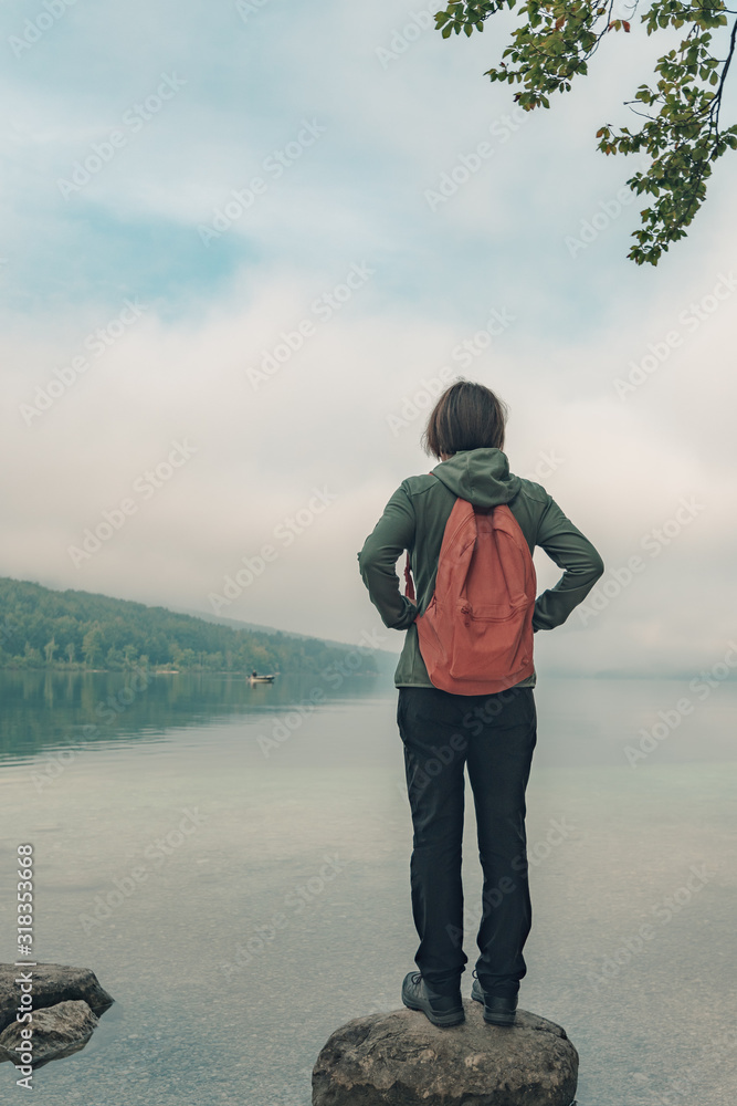 Female hiker standing on the rock and looking at lake