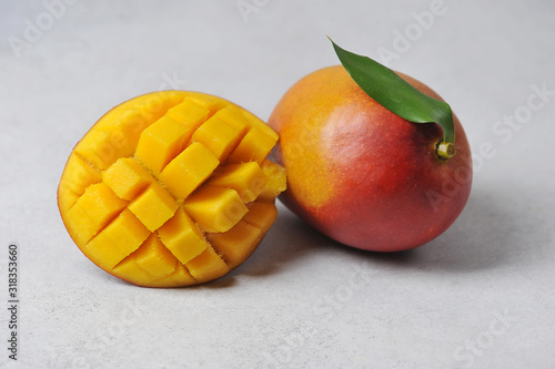 Whole Mango and half the fruit.  Exotic ripe fruit on a light surface.  Light background.  Close-up.