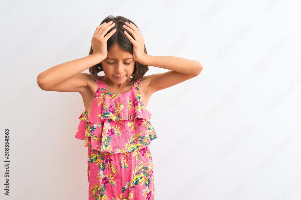 Young beautiful child girl wearing pink floral dress standing over isolated white background suffering from headache desperate and stressed because pain and migraine. Hands on head. Young beautiful child girl wearing pink floral dress standing over isolated white background suffering from headache desperate and stressed because pain and migraine. Hands on head.