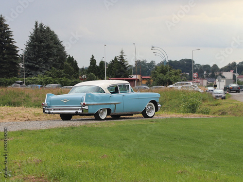 Yaslo, Poland - july 3 2018: Old American classical cadillac of blue color drives throuth a green. Backs headlight with bumper and company logo. Collecting and restoration of old cars. American dream