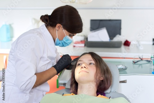 Female dentist treating teeth to patient  young man in chair at dental clinic. Dentistry  healthy teeth  medicine and healthcare concept