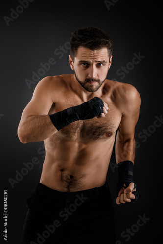 boxer man with bandage on hands training before fight and showing the different movements on black background © producer