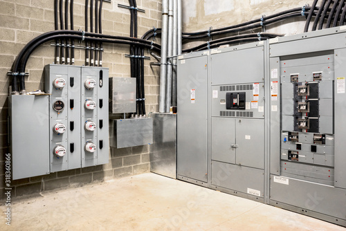 Electrical room of residential or commercial building. Multiple smart meters, main power breaker, meter stacks and cabinets. Perspective view photo