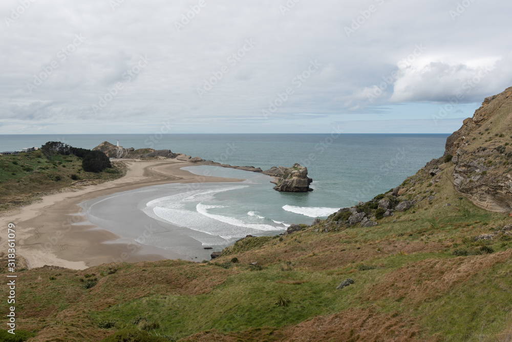 View of the beach and coast at Castle Rock. Castlepoint lighthouse standing above the Pacific Ocean is visible in the background. Castlepoint, Wellington, New Zealand. 