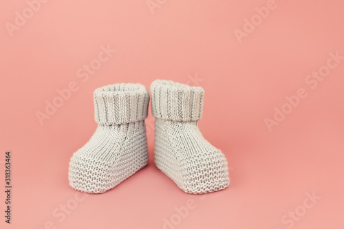 Cute booties for newborn baby girl on pink background.
