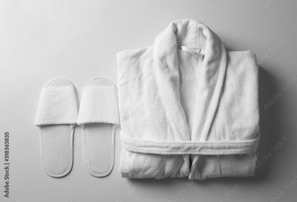 Clean folded bathrobe and slippers on white background, flat lay - obrazy, fototapety, plakaty 