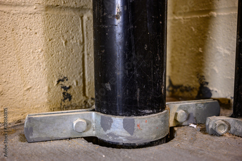 Clamp on metal pipe support bracket on concrete floor