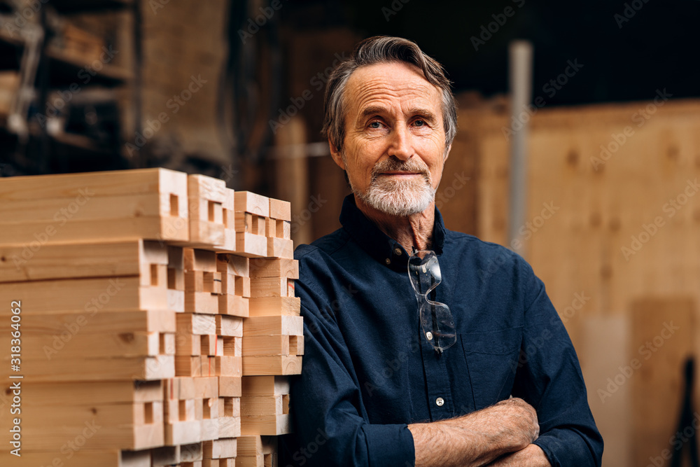 Portrait of confident senior male carpenter standing in his workshop - obrazy, fototapety, plakaty 