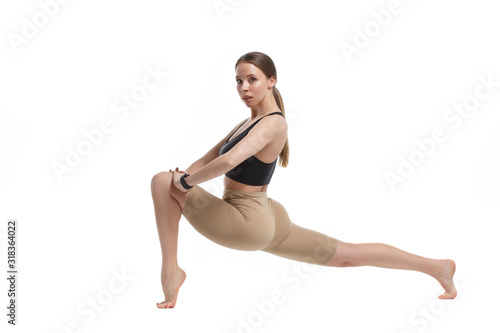 Beautiful slim girl in sportswear performs stretching exercises isolated on a white background.