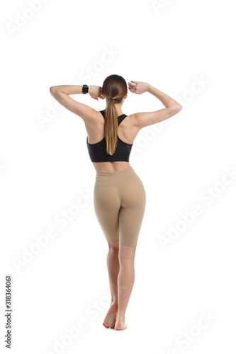Beautiful slender girl in sportswear is standing in full growth isolated from white background view from the back.