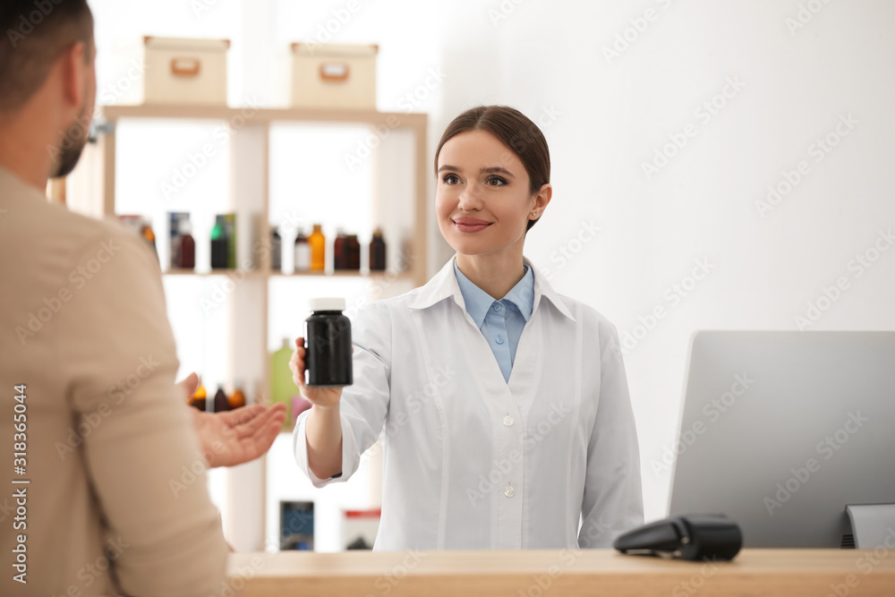 Obraz premium Pharmacist giving medicine to customer in drugstore