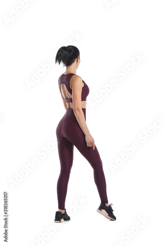 Beautiful slender woman in sportswear is standing in full growth isolated from a white background view from the back.