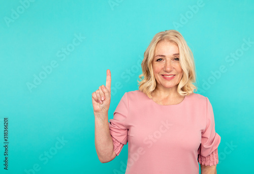 Handsome lady pointing up and smiling isolated over the blue studio