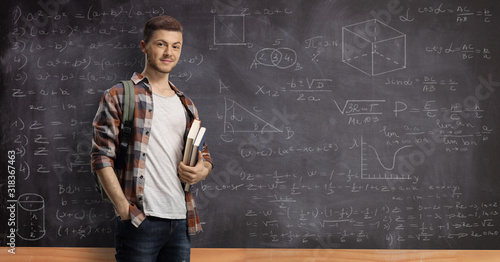 Male student posing in front of a blackboard with math formulas and equations photo