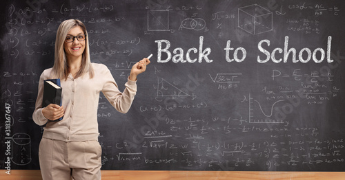 Female teacher pointing to a blackboard with a chalk