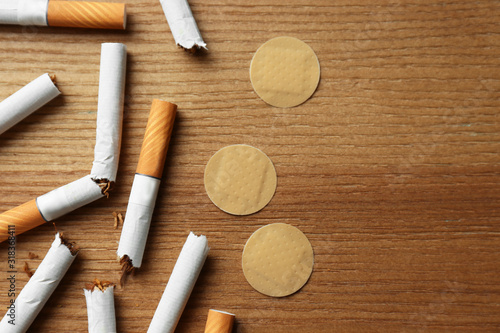 Nicotine patches and broken cigarettes on wooden table, flat lay photo