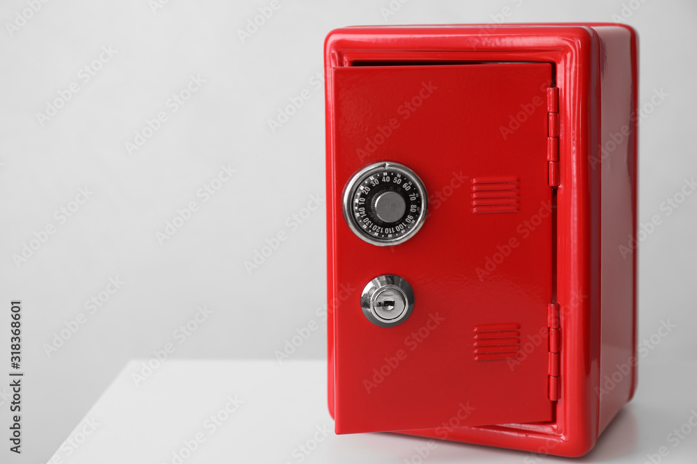 Red steel safe on white table against light background. Space for text Red steel safe on white table against light background. Space for text