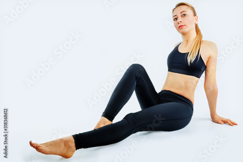 Sport blond girl in tracksuit for sport exercises on a white background