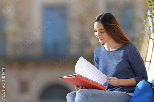 Happy student studying reading notes in a campus
