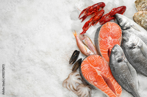 Fresh fish and seafood on ice, flat lay. Space for text