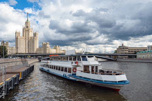 Pleasure boat sails from the pier. The beginning of the water tour of Moscow. Tourist attractions of Moscow. High-rise building in the center of the capital. Travel to Russia. Cloudy day.