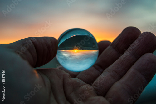 glass ball in hand on sunset
