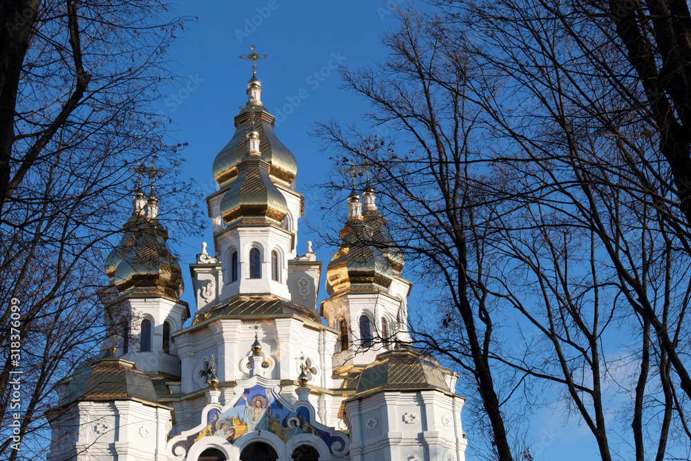 Against the blue sky, a white church with golden domes. Against the blue sky, a white church with golden domes.