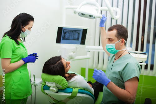 The dentist man are treating teeth to client in dental office