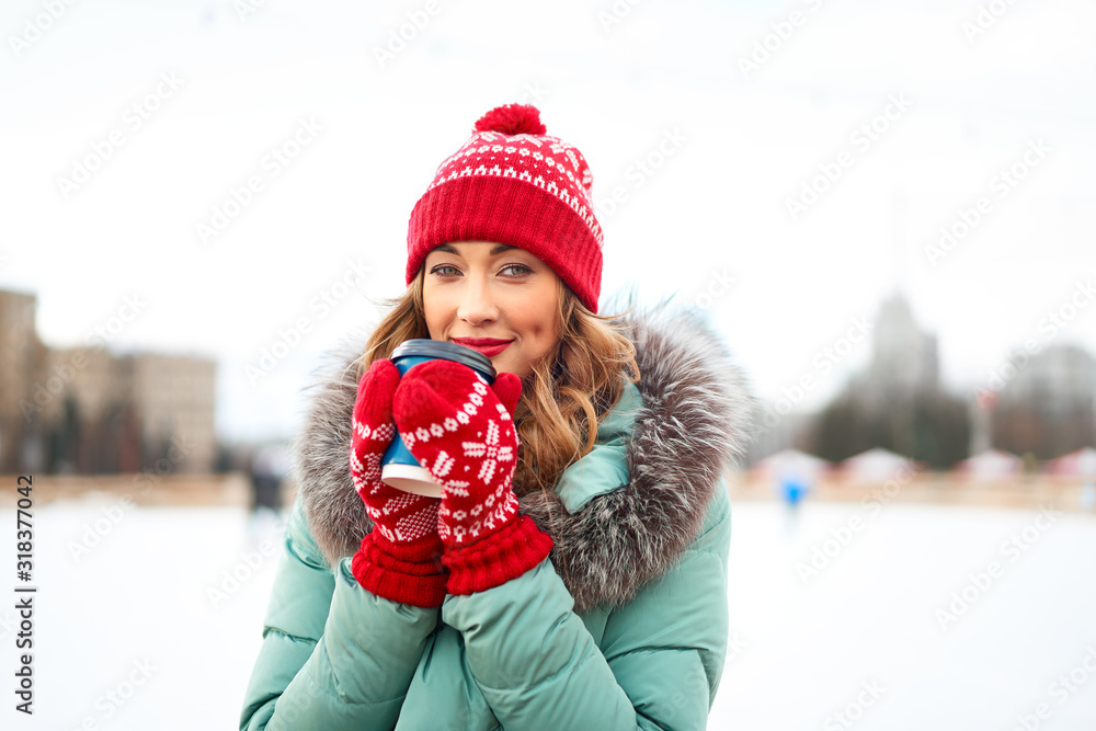 Beautiful lovely middle-aged girl with curly hair warm winter jackets stands ice rink background Town Square. Beautiful lovely middle-aged girl with curly hair warm winter jackets stands ice rink background Town Square.