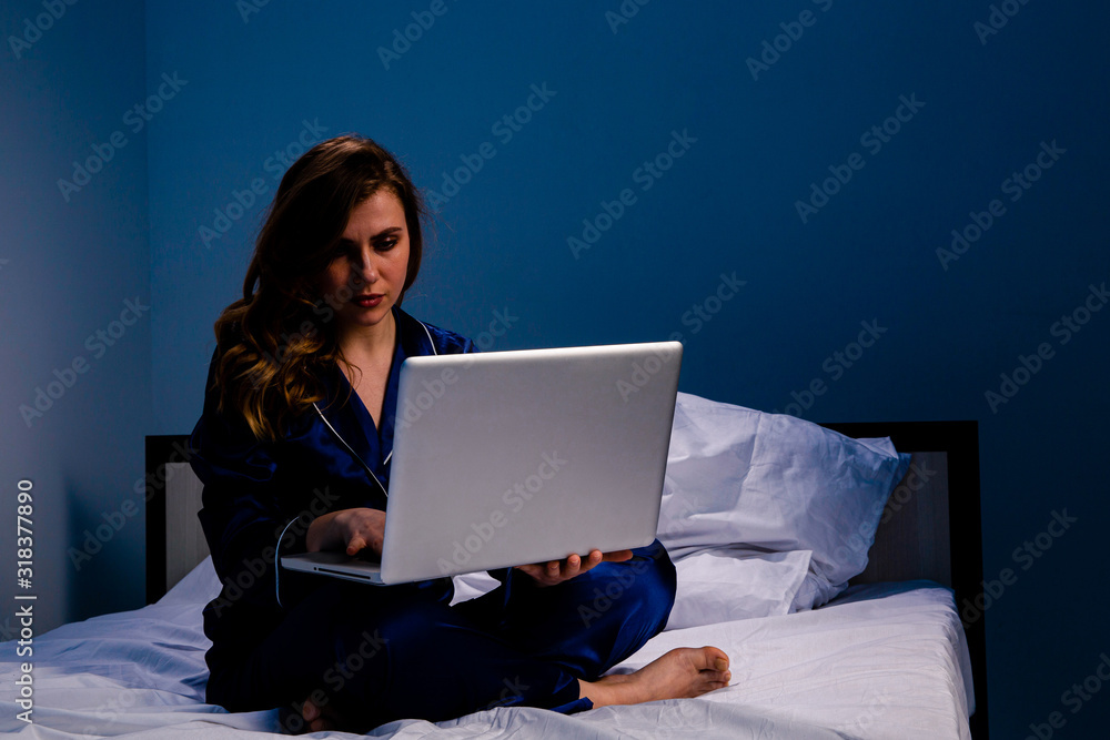 Picture of the woman suffering of insomnia and feeling asleep and working on a laptop at home sitting on the bed Picture of the woman suffering of insomnia and feeling asleep and working on a laptop at home sitting on the bed