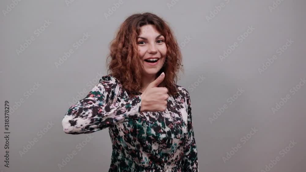 Cheerful caucasian young woman keeping fists, smiiling, looking happy over isolated gray background in fashion shirt. Lifestyle concept Cheerful caucasian young woman keeping fists, smiiling, looking happy over isolated gray background in fashion shirt. Lifestyle concept