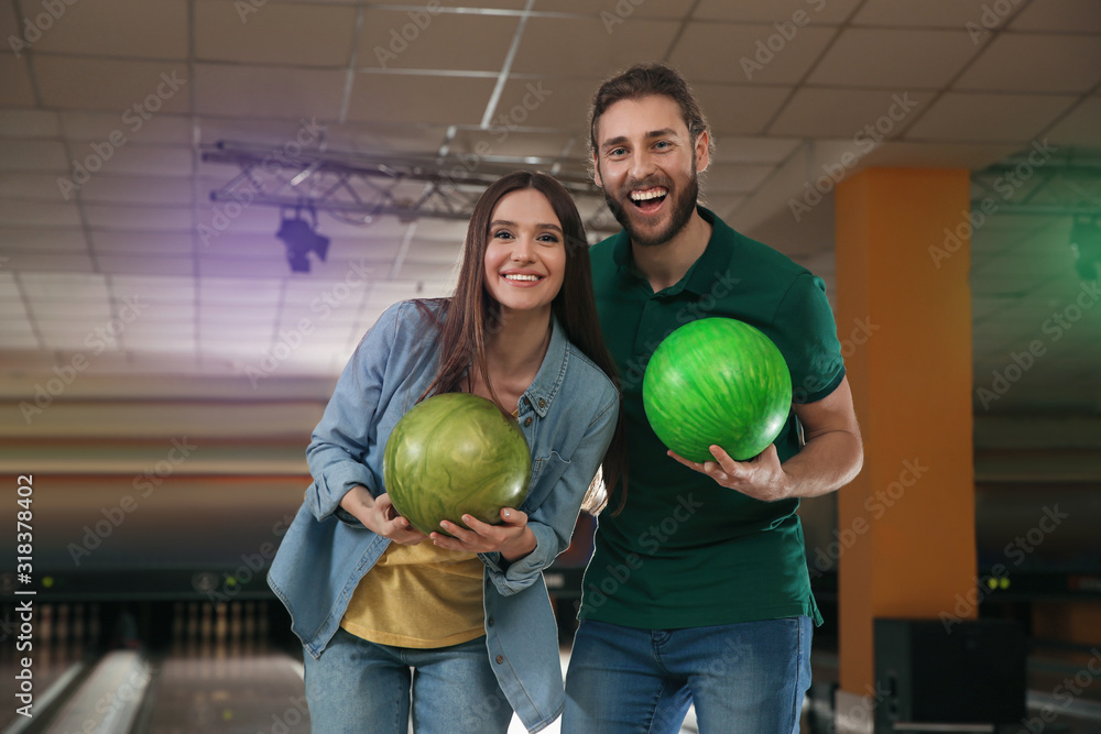 Fototapeta premium Happy young couple with balls in bowling club